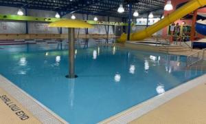 Side view of indoor pool. There is a large yellow water slide to the side of the pool.