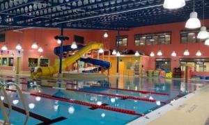 Interior of indoor pool facility. There are some water slides on the far end of the pool and various swim lanes divided by floating dividers.